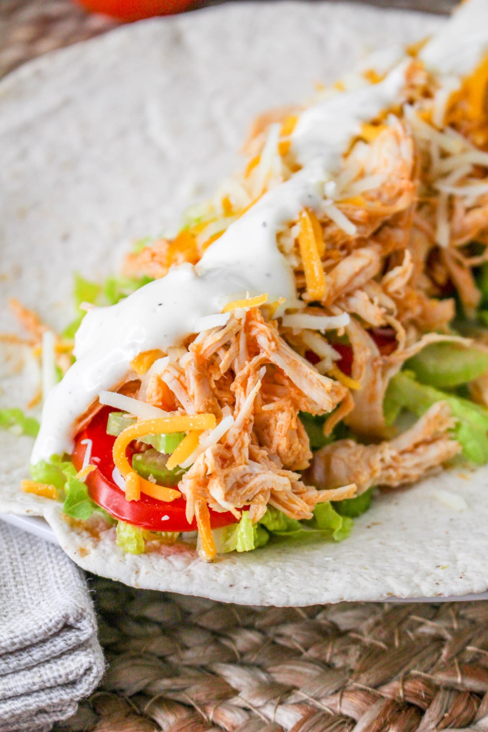 Buffalo Chicken Wrap with ranch dressing, cheese, tomatoes, lettuce, and celery on a flour tortilla.