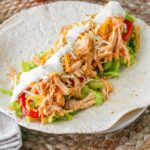 Buffalo Chicken Wrap with ranch dressing, cheese, and vegetables on a flour tortilla.