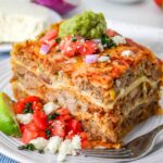 Carnitas Casserole: a slice of Mexican Pulled Pork Casserole on a plate with tomatoes.