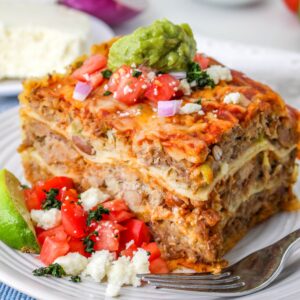 Carnitas Casserole: a slice of Mexican Pulled Pork Casserole on a plate with tomatoes.