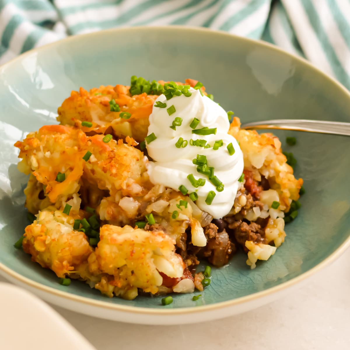 Recipe: Chili Cheese Tater Tot Casserole in a bowl with sour cream and chives.