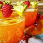 Pineapple Mango Cocktail garnished with strawberries and pineapple wedges.