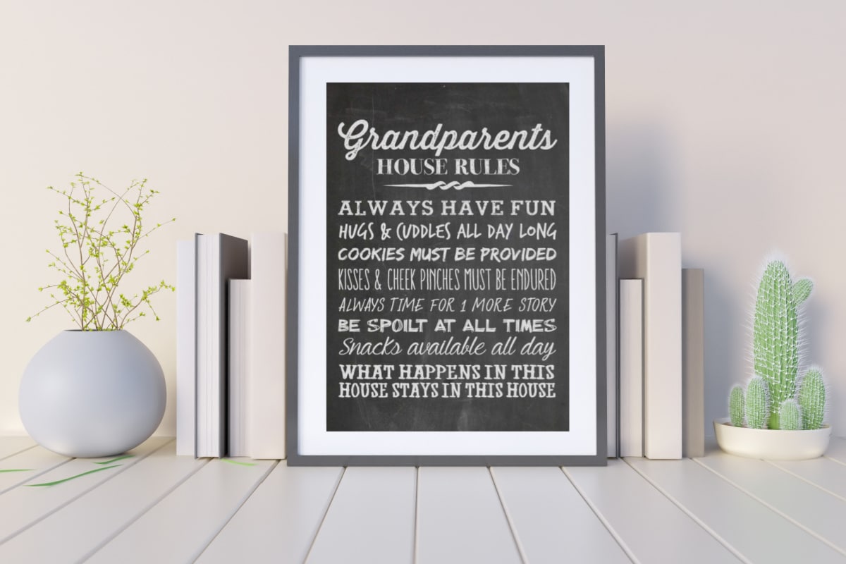 Grandparents House Rules framed chalkboard print on a shelf with books and plants.