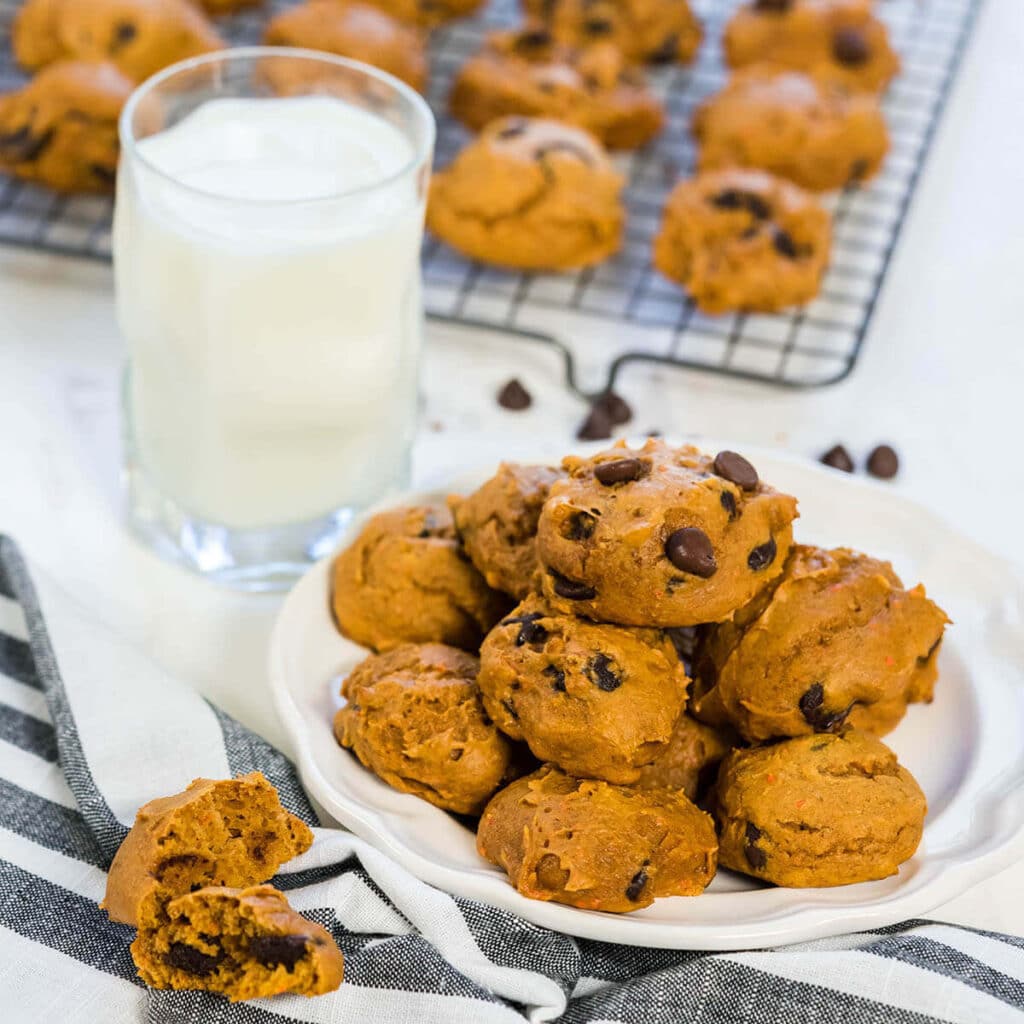 Chewy Pumpkin Chocolate Chip Cookies on a plate with a glass of milk nearby.