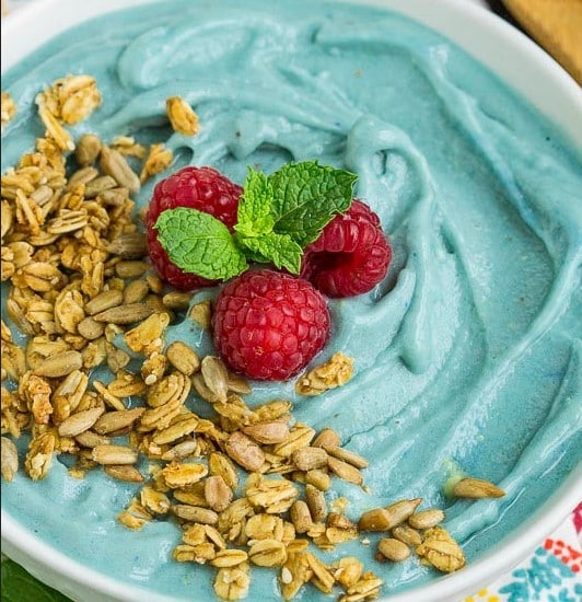 Close up of granola and raspberries on top of a Blue Spirulina Mermaid Smoothie Bowl.