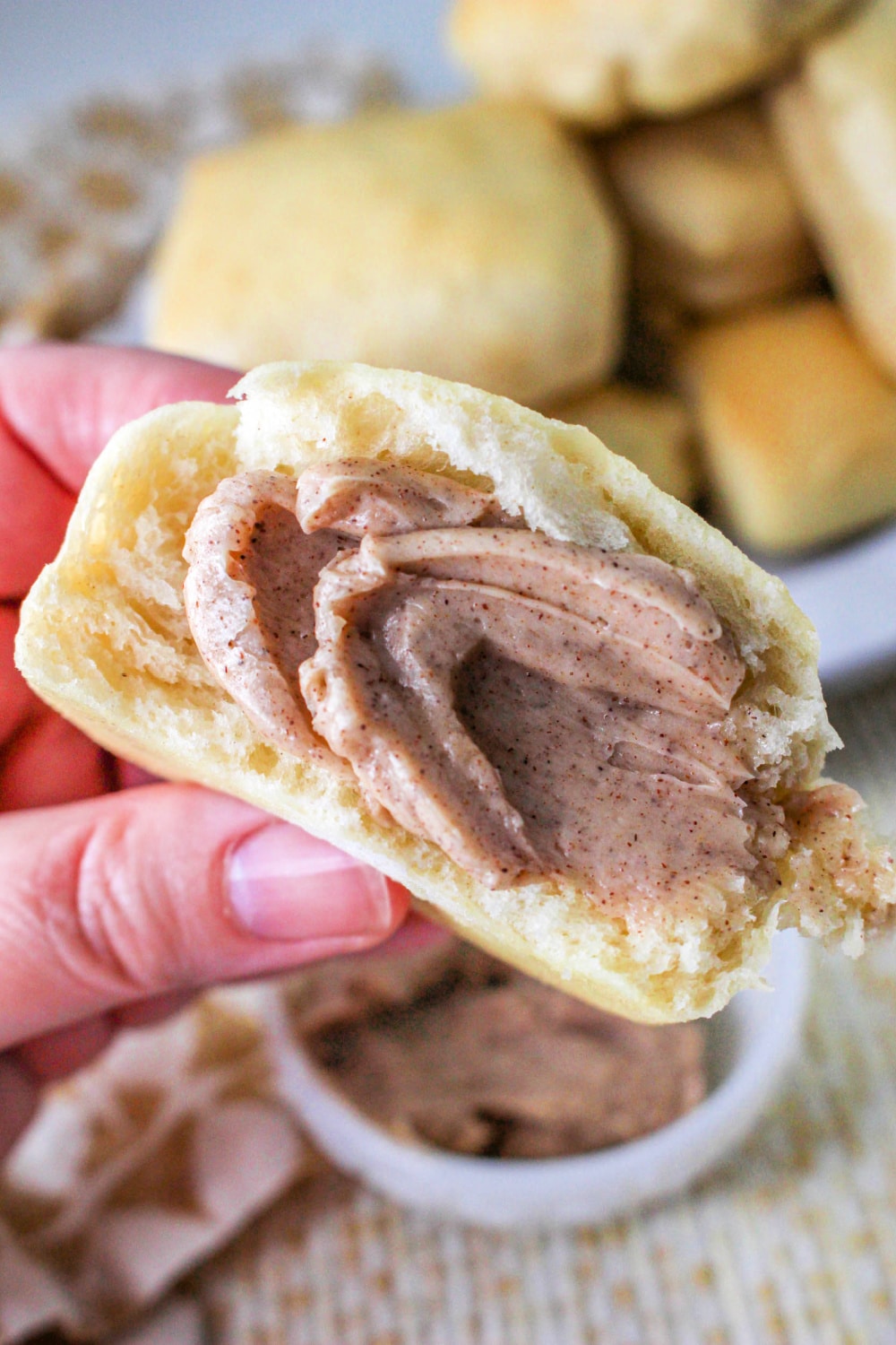 Hand holding a roll with Texas Roadhouse Cinnamon Butter on it.