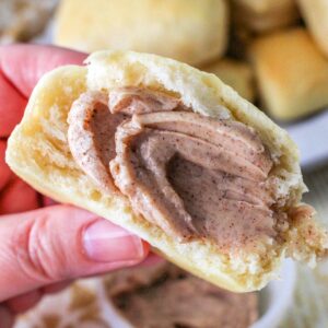 Hand holding a roll with Texas Roadhouse Butter on it.