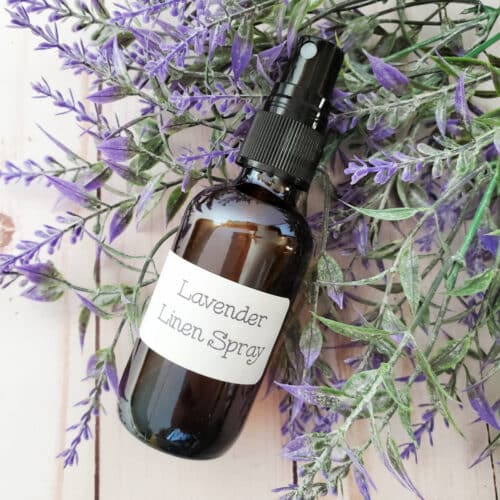 Lavender Linen Spray in a spray bottle next to faux lavender.