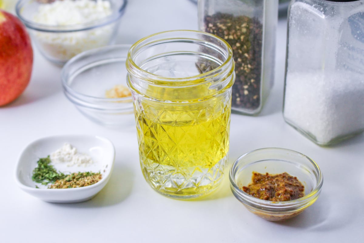 Ingredients to make homemade lemon mustard vinaigrette on a countertop, including stone ground mustard and olive oil.