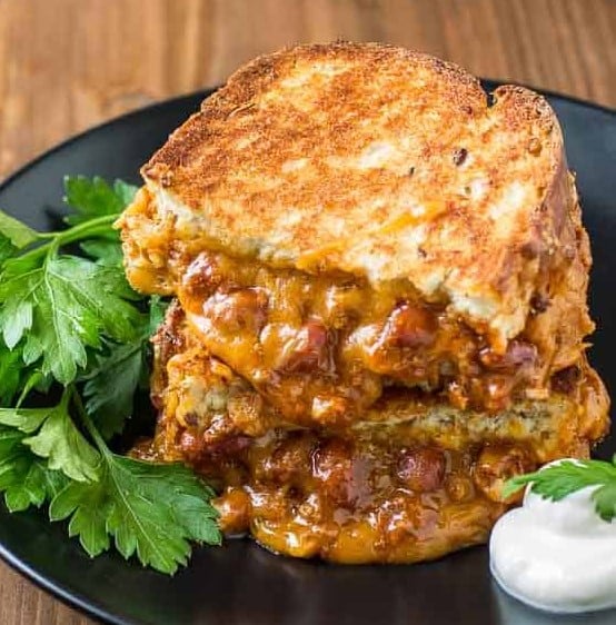 Chili Cheese Grilled Sandwich on a black plate.