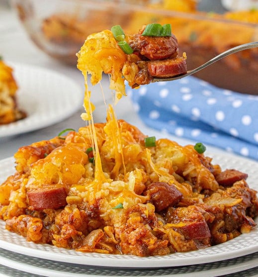 Fork holding a cheesy bite of Chili Dog Tater Tot Casserole.