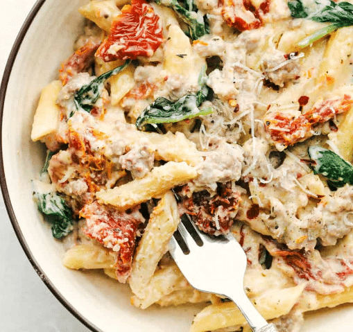 Top down view of Creamy Tuscan Sausage Pasta on a plate with a fork.
