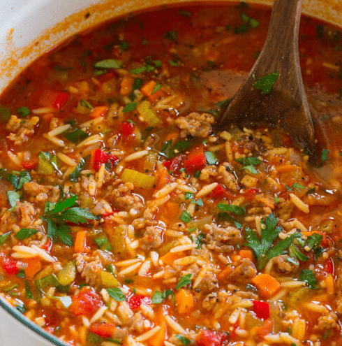 Pot of Italian Sausage Soup with a wooden spoon.
