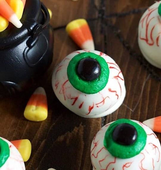 No Bake Oreo Truffle Eyeballs on a table top next to candy corn.
