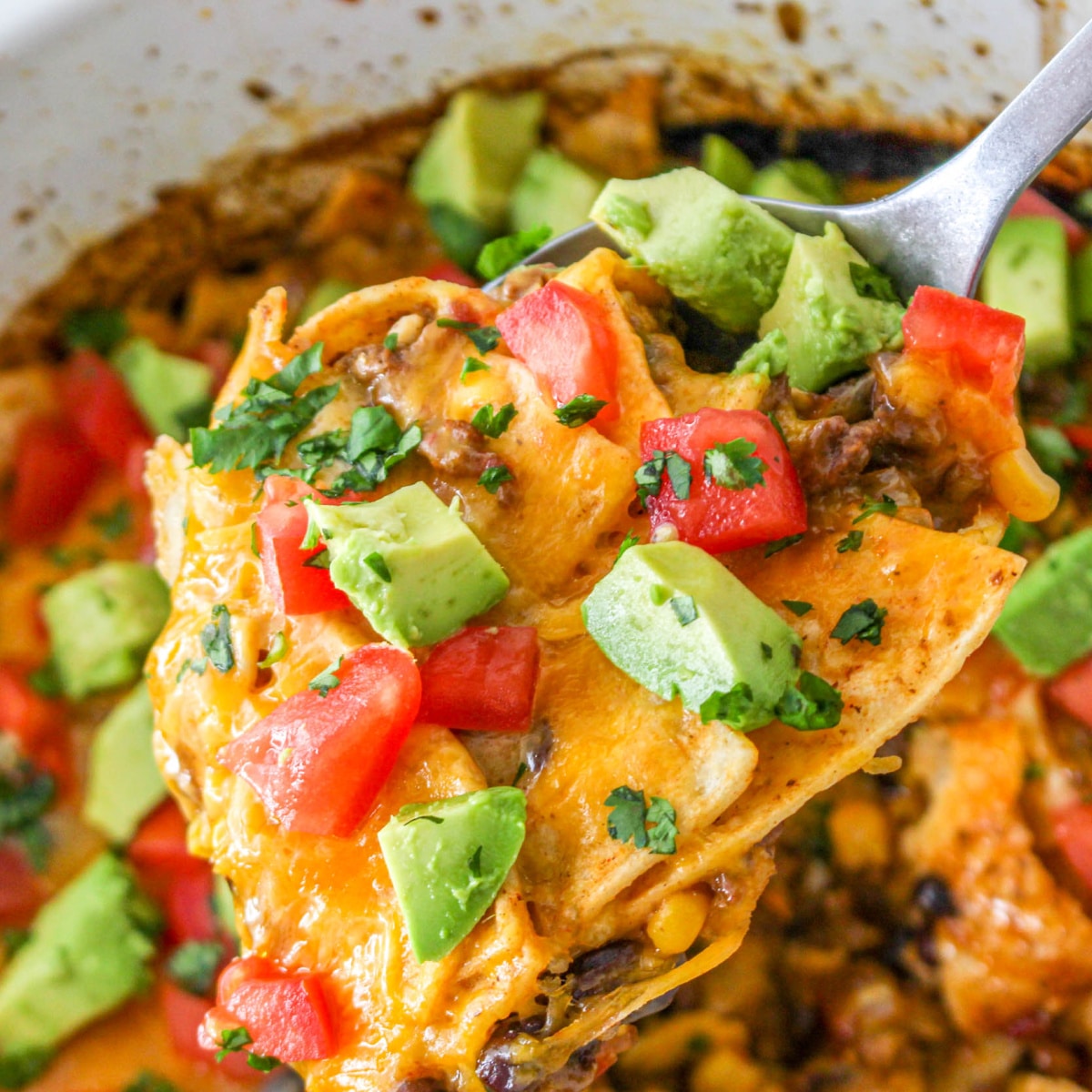 Spoonful of Slow Cooker Taco Casserole topped with tomatoes and avocado.