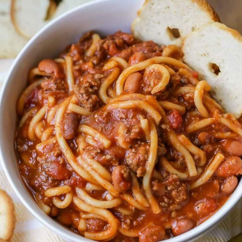 Bowl of chili spaghetti with bread.