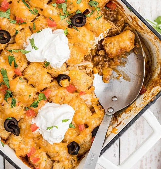 Mexican Tater Tot Casserole dish with a serving spoon.