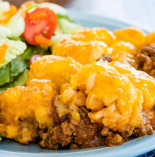 Cheesy Sloppy Joe Tater Tot Casserole on a plate with a salad.