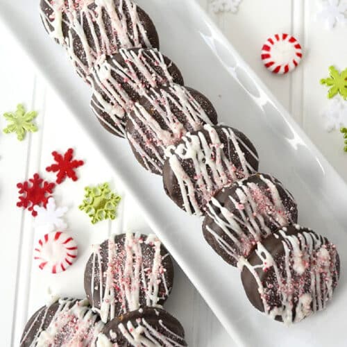 Plate full of chocolate peppetmint ritz cookies decorated for the holidays.