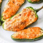Close up of Sausage Stuffed Jalapenos on a white plate.