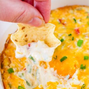 Hand holding a chip with Cream Cheese Corn Dip.