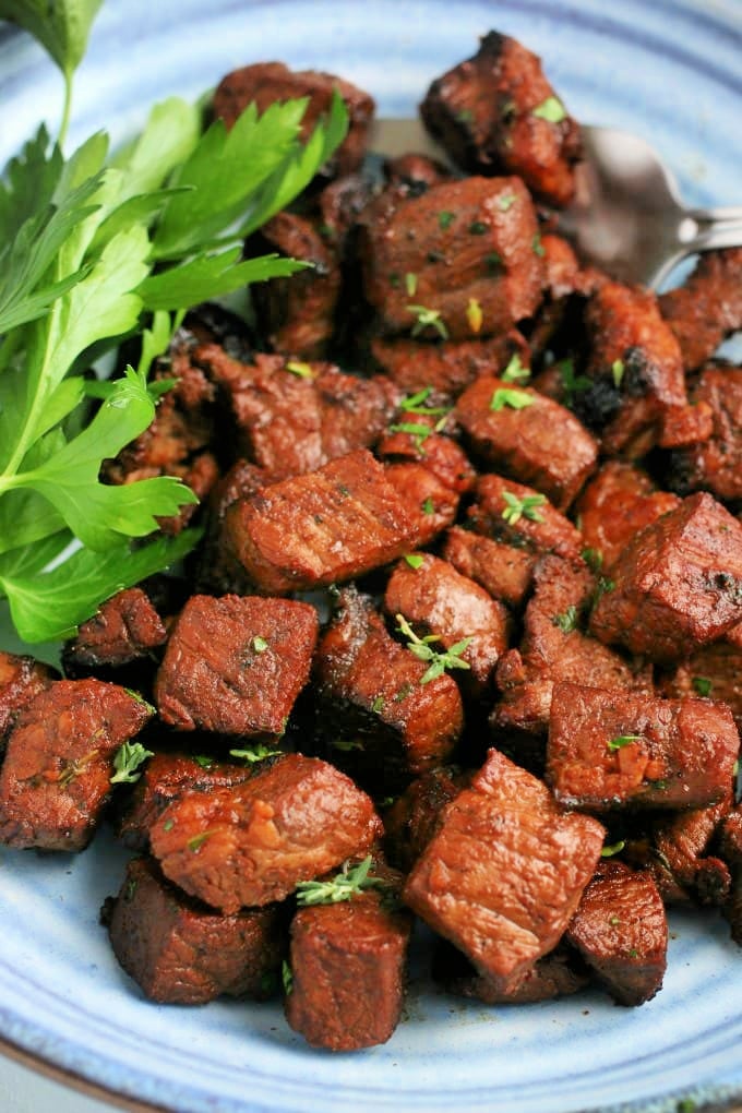 Steak Bites with Garlic Butter on a plate with parsley.