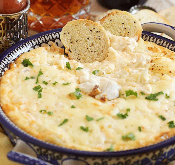 Close up of hot crab dip in a bowl with crostini on the side.