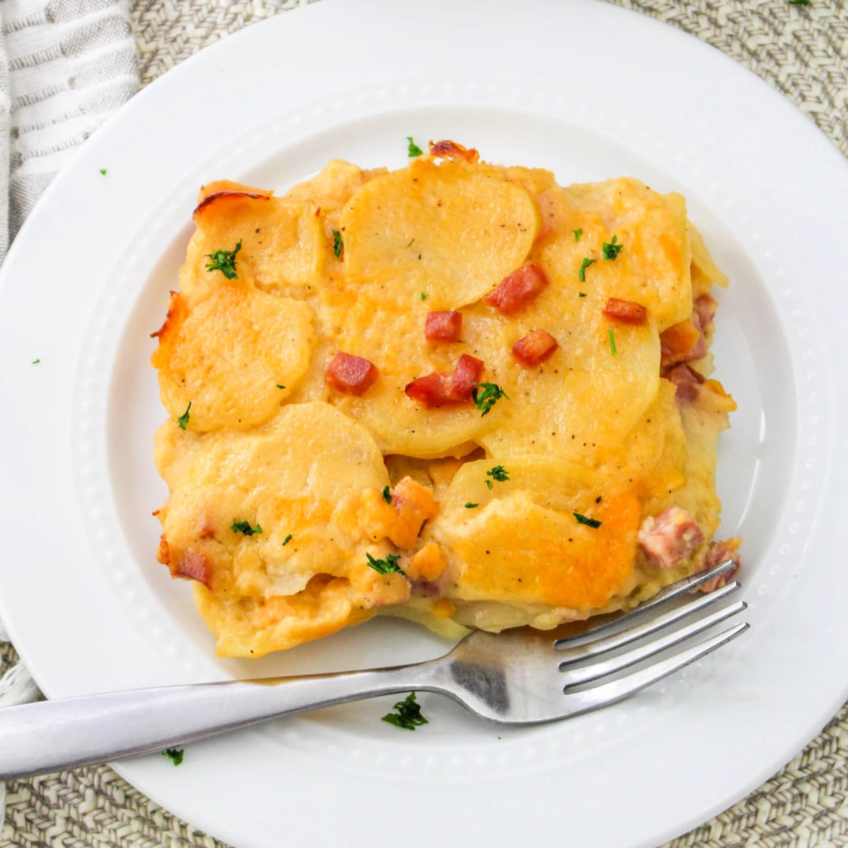Top down view of cheesy Ham and Potatoes Au Gratin on a plate with a fork.