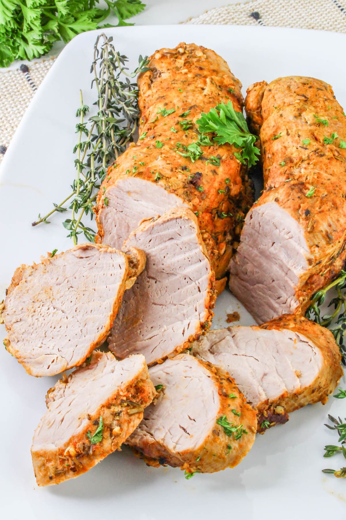Dutch Oven Roasted Pork Tenderloin on a platter with fresh herbs.