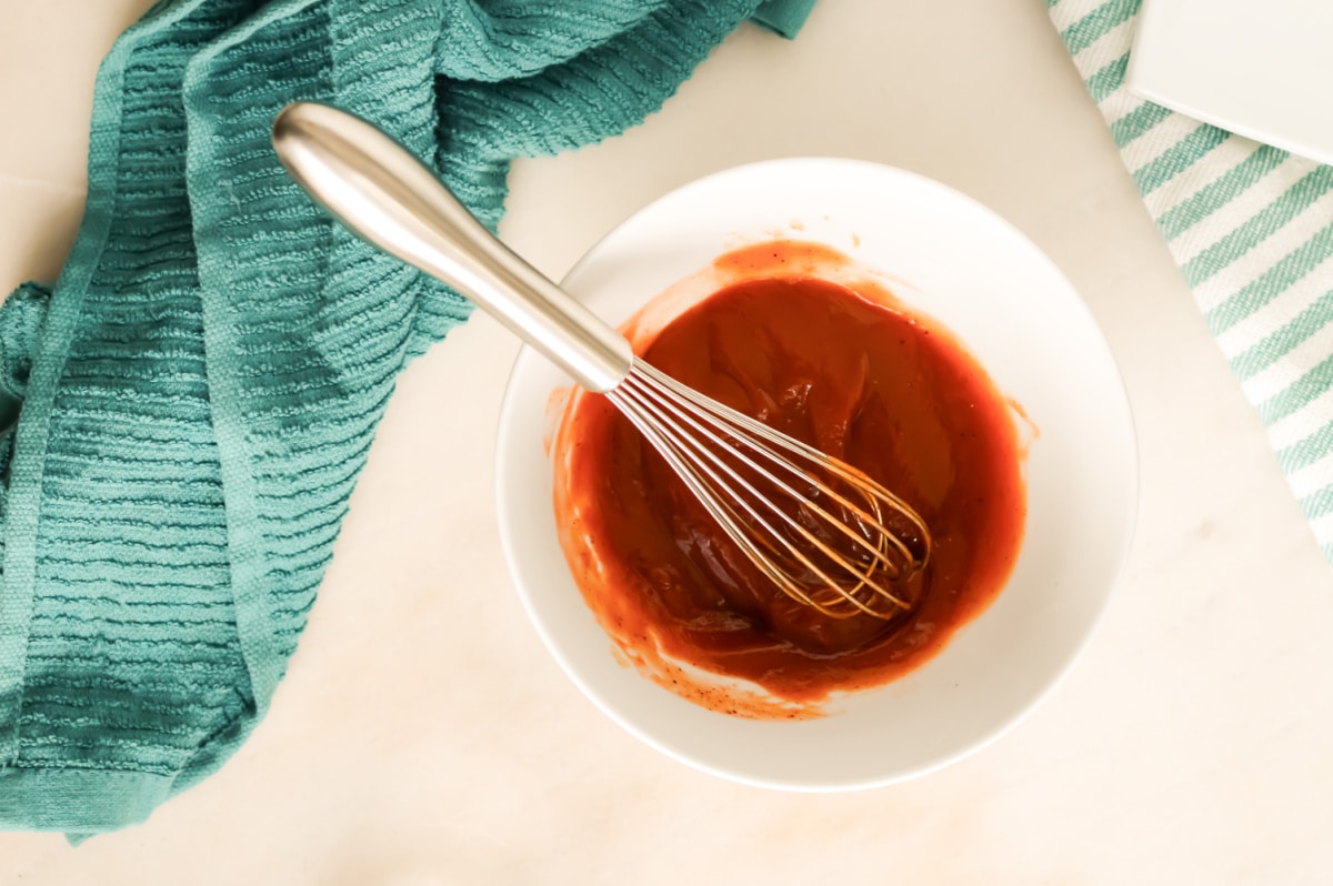 Small bowl of spicy ketchup with a whisk.