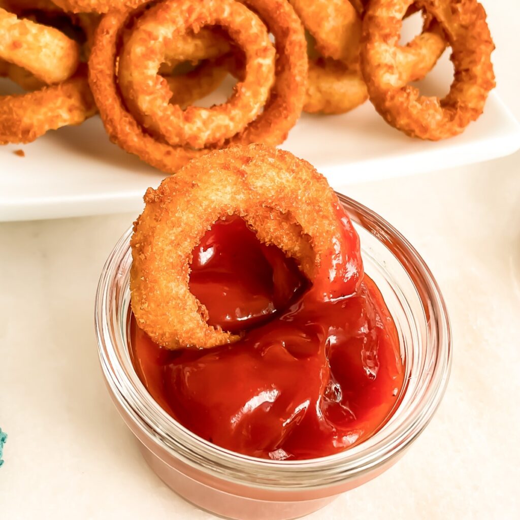 Spicy Ketchup Recipe -close up of an onion ring in a small bowl of ketchup.