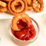 Spicy Ketchup Recipe -close up of an onion ring in a small bowl of ketchup.