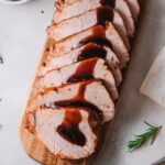 Top down sliced Pork Loin on a cutting board with brown sugar balsamic glaze.