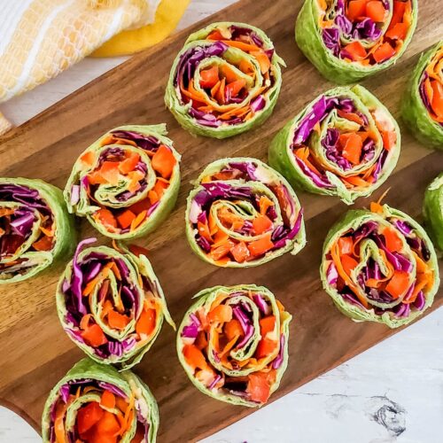 Close up of Hummus Pinwheels with veggies on a cutting board.
