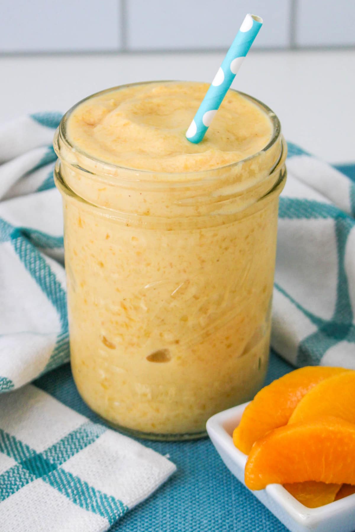 Peaches and Cream Smoothie in a mason jar with a straw.