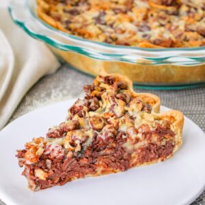 Close up of chocolatey Texas Trash Pie with coconut, pretzels, and pecans on a plate.