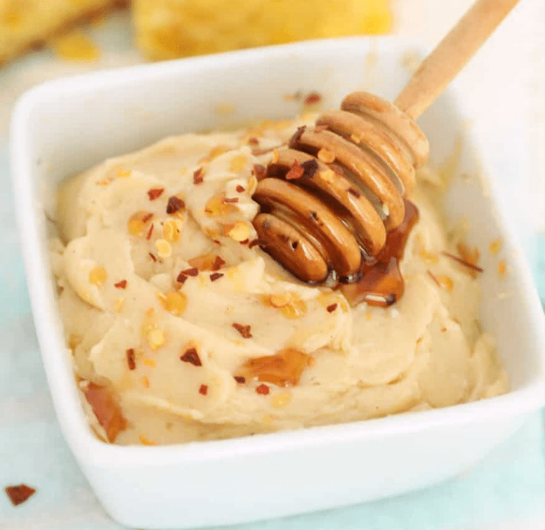 Hot honey butter in a square bowl with red pepper flakes sprinkled on top.