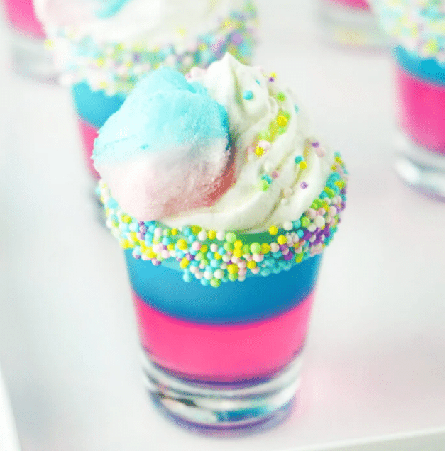 Close up of cotton candy jello shots with whipped cream.