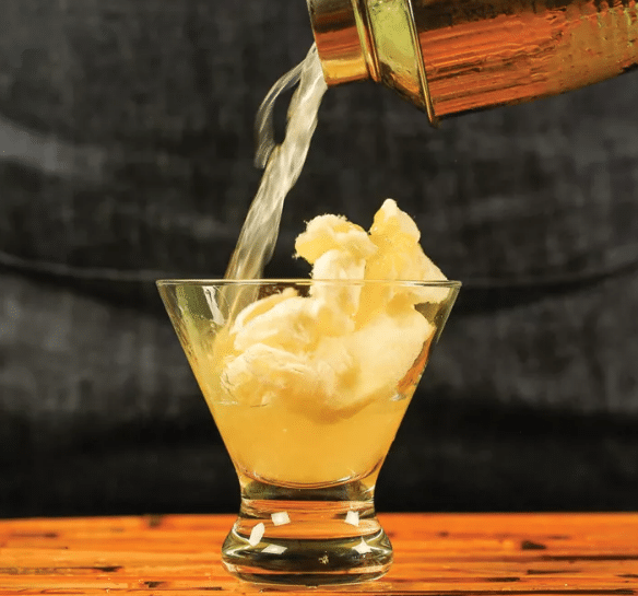 Cocktail shaker pouring a cotton candy daiquiri into a glass.