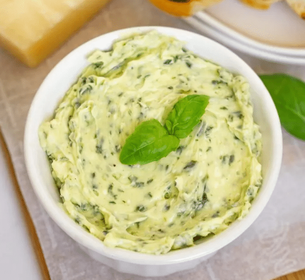 Top down view of Pesto Compound Butter in a small dish garnished with basil.