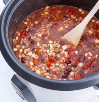 Rice cooker with tortilla soup and wooden spoon.