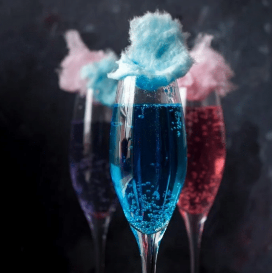 Champagne flutes full of unicorn cotton candy drinks.