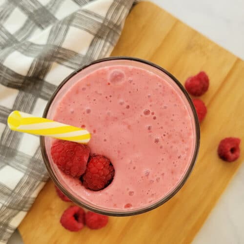 Top down view of a Raspberry Smoothie with a striped straw.