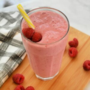 Close up of Raspberry Smoothie in a tall glass with a straw.