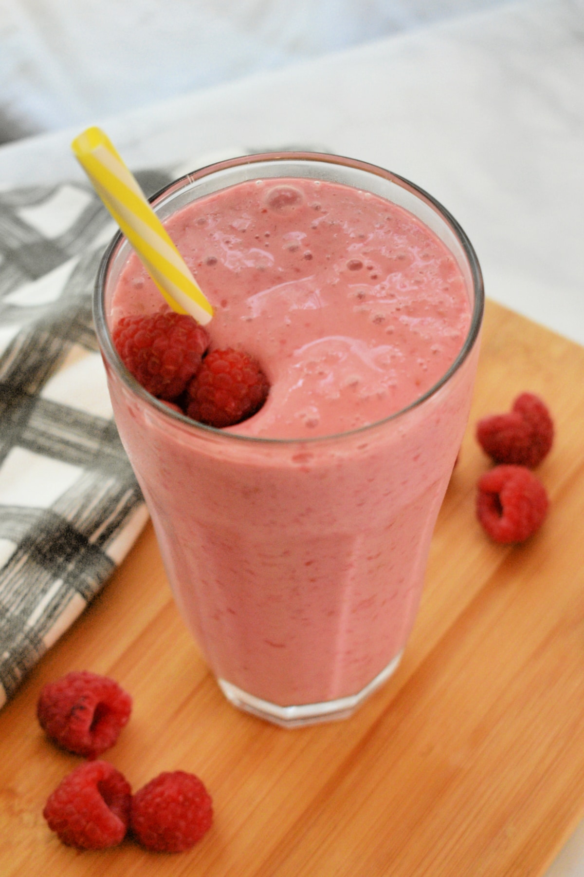 Raspberry Smoothie in a tall glass with a straw.