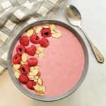 Top down view of Raspberry Smoothie Bowl with berries and almonds.