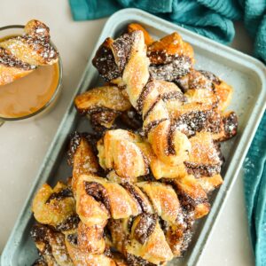 Close up of Nuetlla Puff Pastry Twists dusted with powdered sugar on a serving tray.