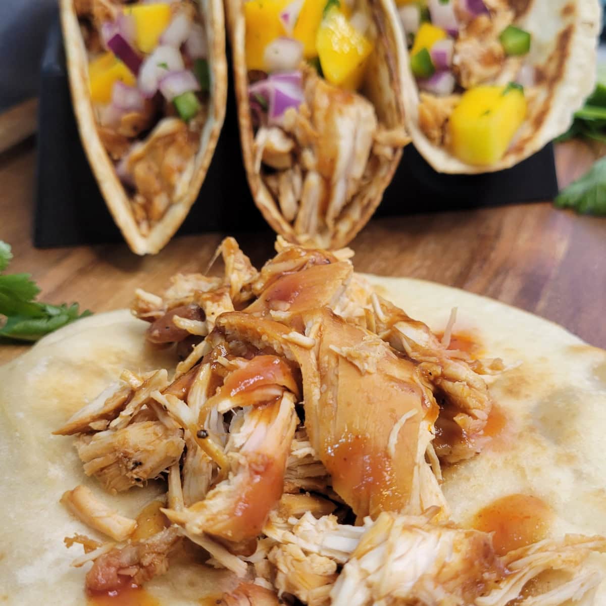 Close up of shredded BBQ chicken on a toasted tortilla.