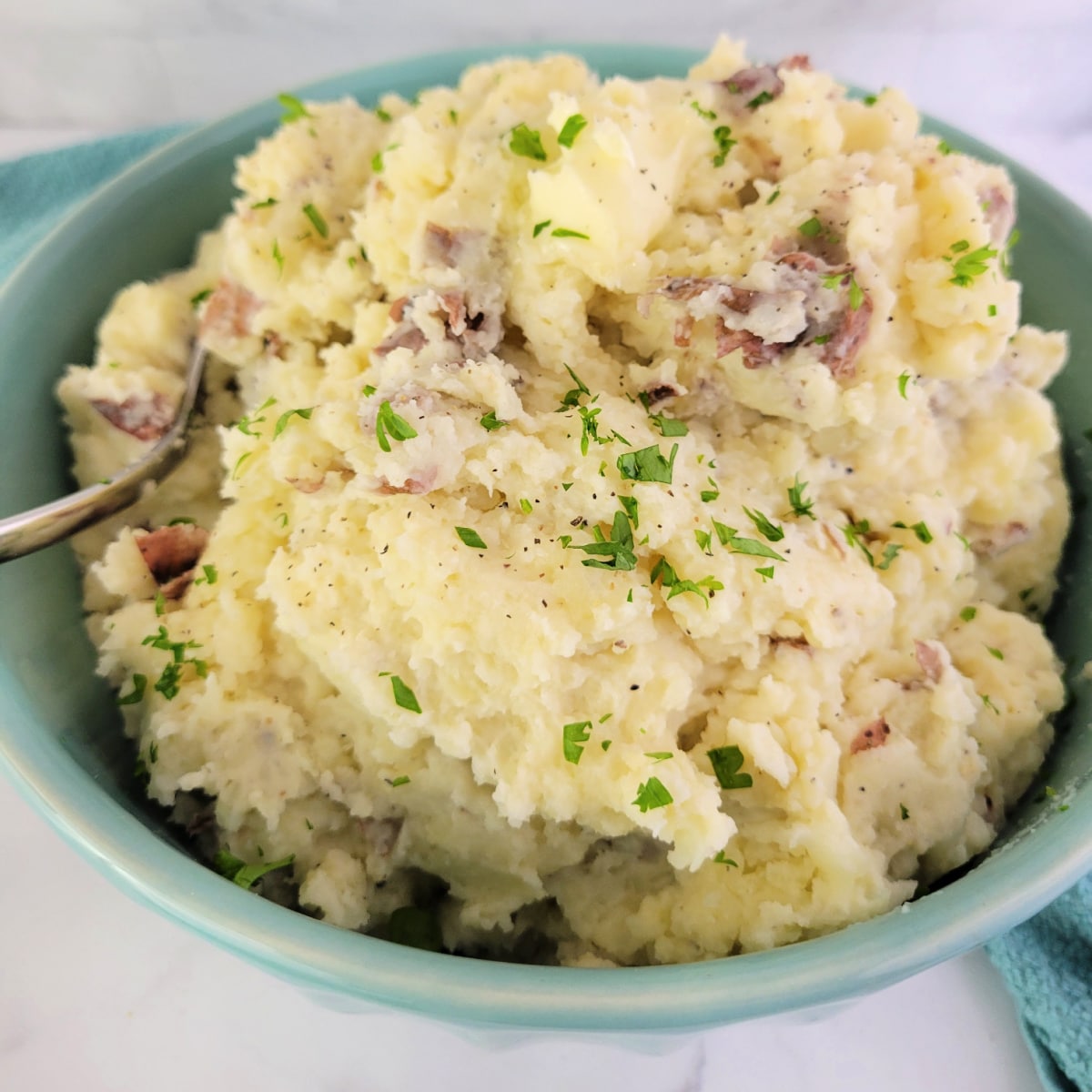 Close up of Red Skin Mashed Potatoes in a bowl with a spoon.
