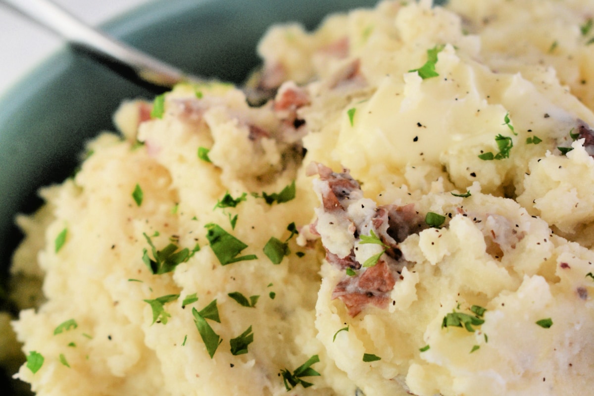 Close up of Red Skin Smashed Potatoes in a bowl with a spoon.